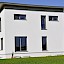 Niedrigstenergiehaus in Petzenkirchen  – Holzriegelhaus mit gekröpfter Attika-Konstruktion, Verwendung von Stahlteilen für zierliche Ausführung, Putzfassade
